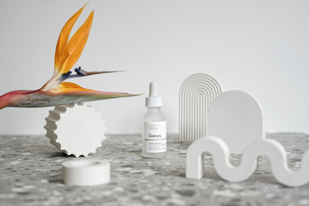 Skincare serum bottle styled with abstract white props and a bird of paradise flower