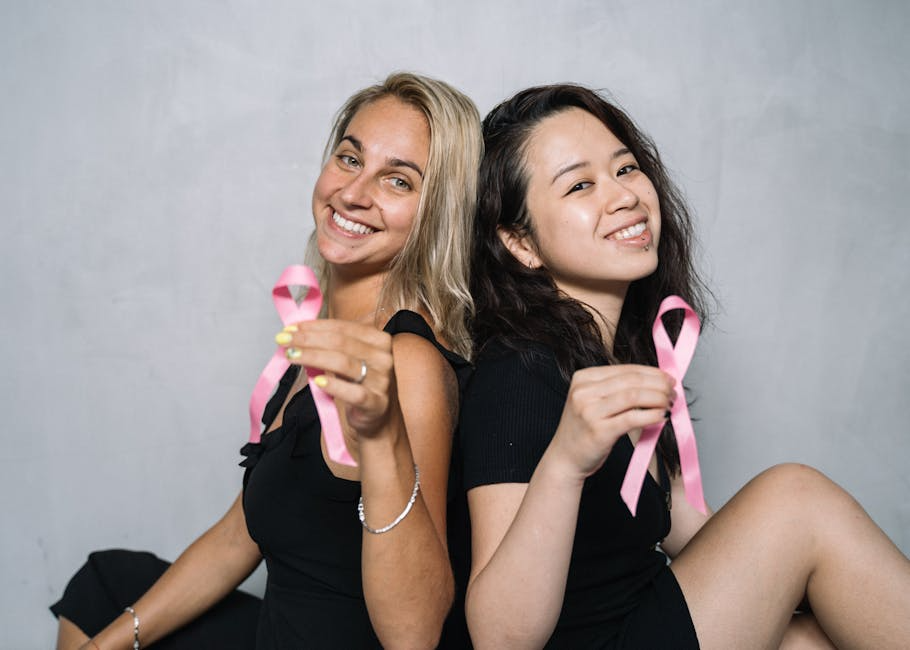 Two women holding pink ribbons.