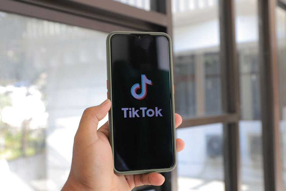 Hand holding phone displaying TikTok logo